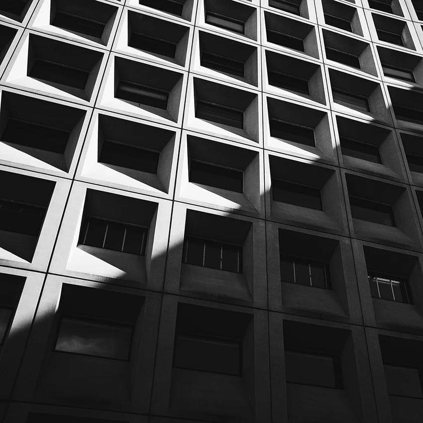 Black-and-white geometric building facade with recessed square windows.